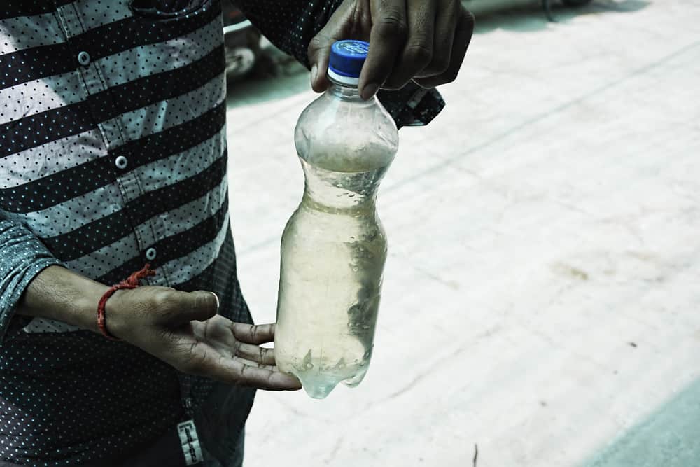 person holding contaminated water in a bottle