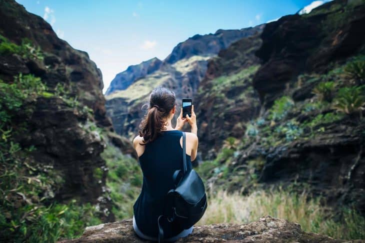 Woman taking photo of mountains landscape using phone