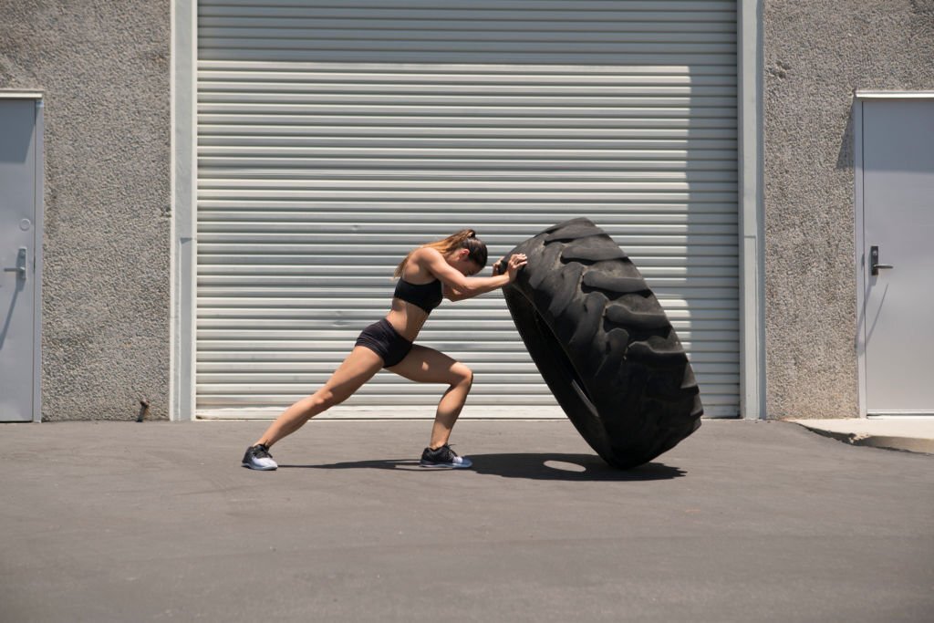 woman pushing tyre, woman showing power
