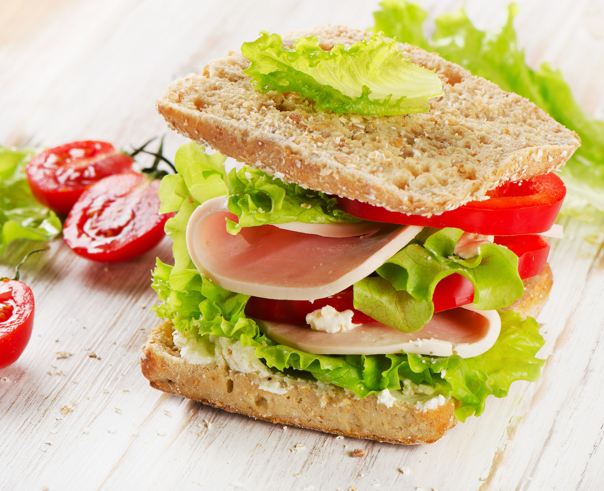 Sandwich with turkey and fresh vegetables on a wooden table