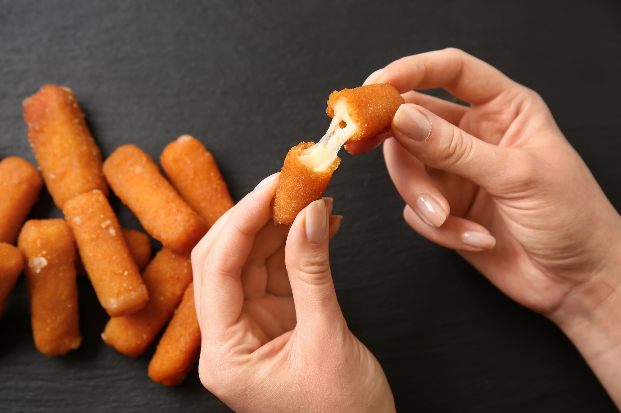 Woman eating tasty mozzarella sticks, closeup
