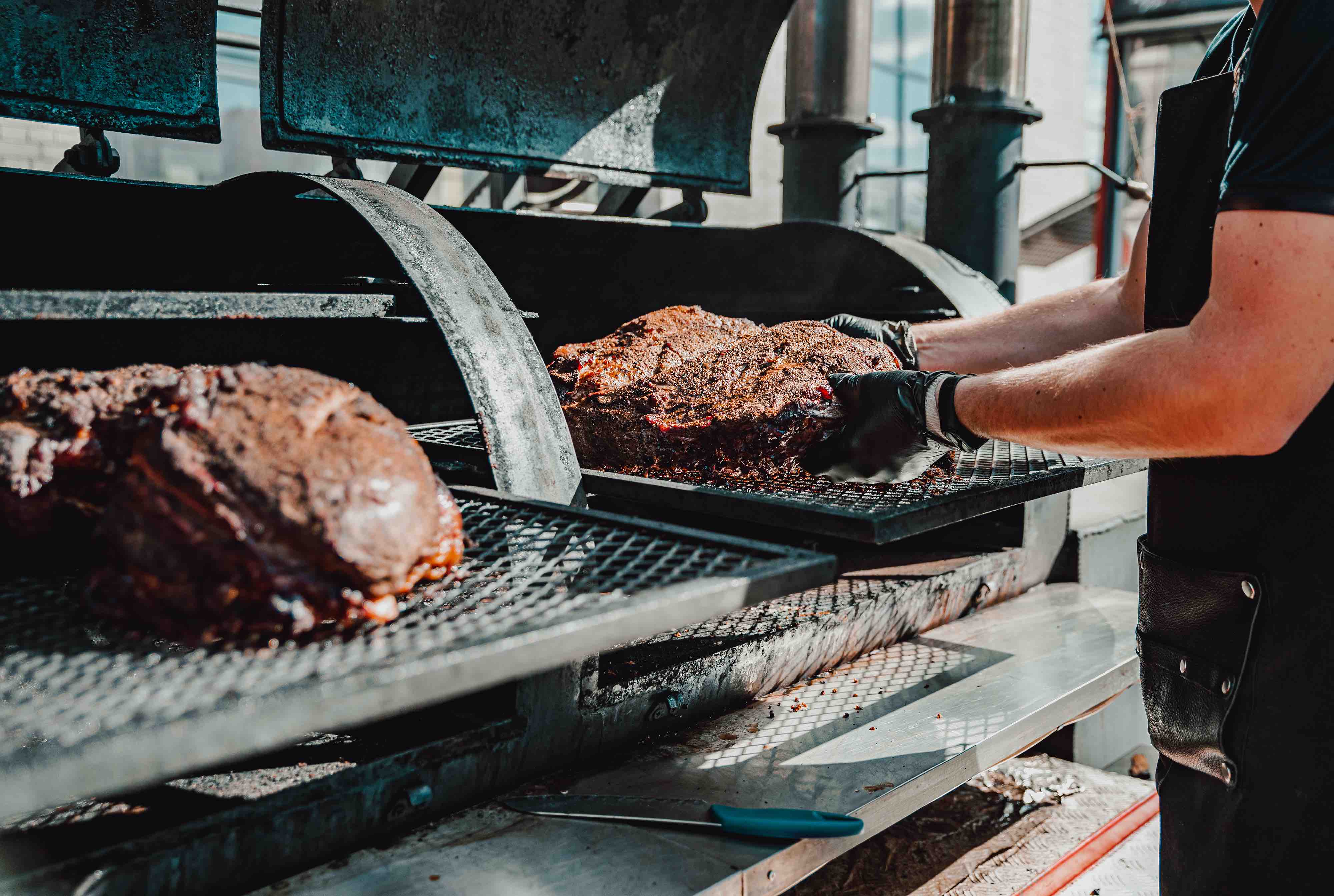 Chef hand cooking grilled beef meat in BBQ smoker outdoor