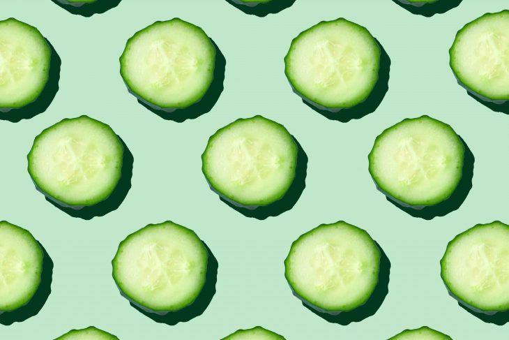 Regular seamless pattern of cucumber slices on a pastel mint background.Photo collage,hard light, shadow,pop art design. Food blog, vegetable background. Printing on fabric, wrapping paper.Top view.