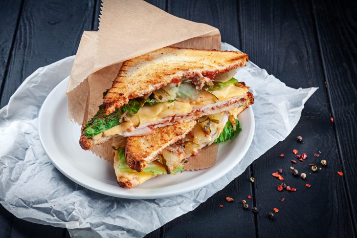 Close up on grilled sandwich with chicken and melted cheese and lettuce