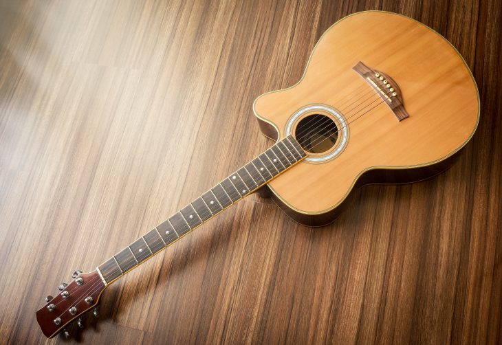 Acoustic guitar laid on wooden floor