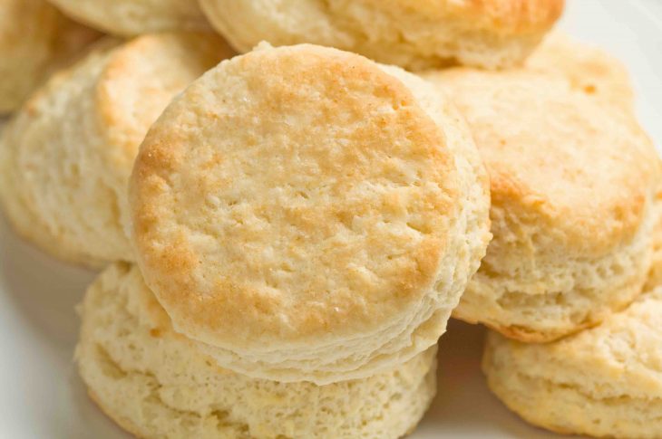 Light tasty golden homemade buttermilk biscuits arranged on rectangular platter.