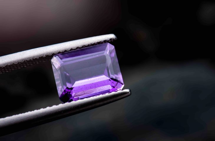 Purple amethyst gemstone jewelry photo with dark lighting background.