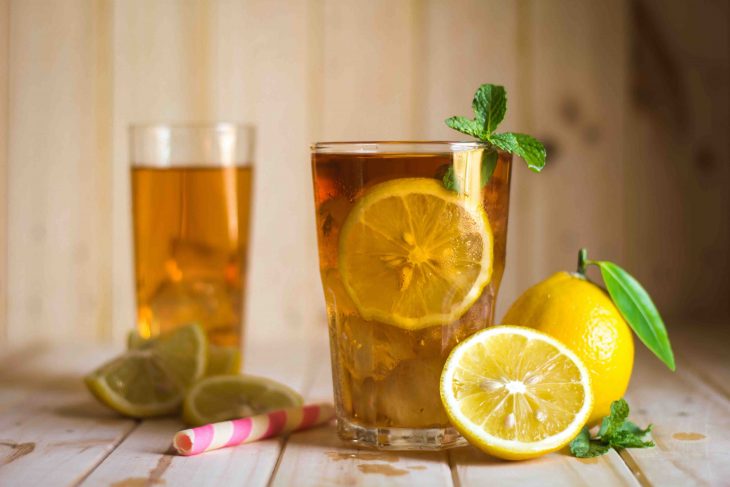 Glasses of ice tea with lemon slices on wooden background
