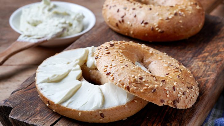 Bagel with cream cheese on wooden board