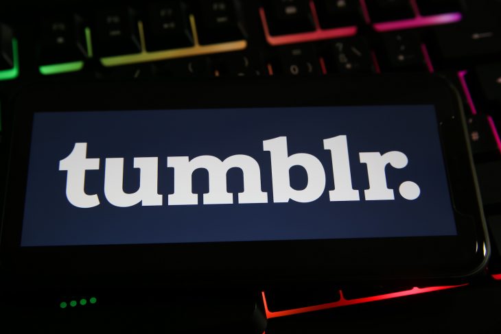 Closeup of mobile phone with logo lettering of tumblr blogging platform on computer keyboard