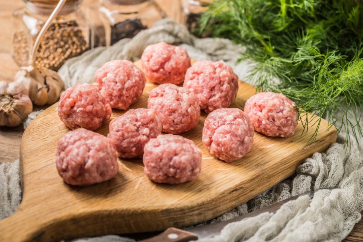 Raw meatballs on the wooden cutting board