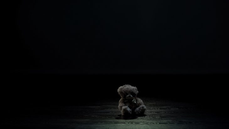 Teddy bear toy in dark room, loneliness and lost childhood concept, sadness