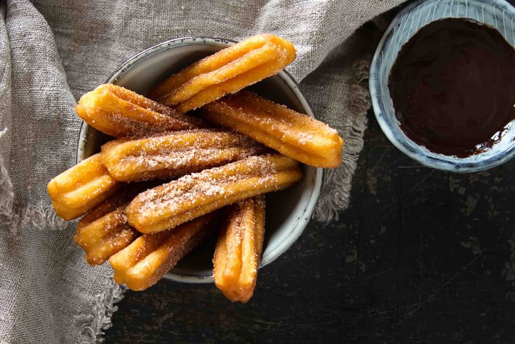 Traditional Mexican dessert churros with chocolate sauce. Dark background.