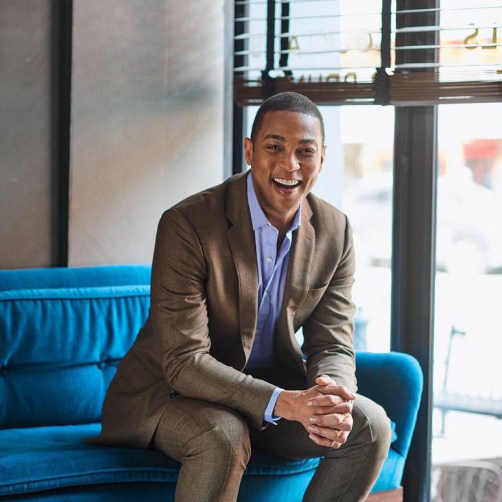 don lemon smiling brightly while sitting on couch
