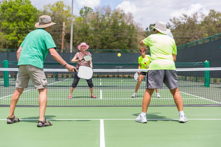 four elderly persons playing pickle ball in a court