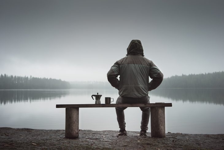 man sitting by the lake alone