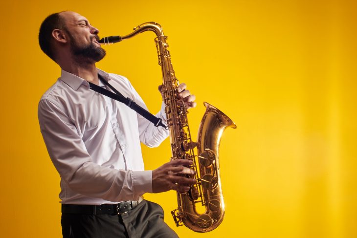 professional musician saxophonist man in white shirt plays jazz music on saxophone
