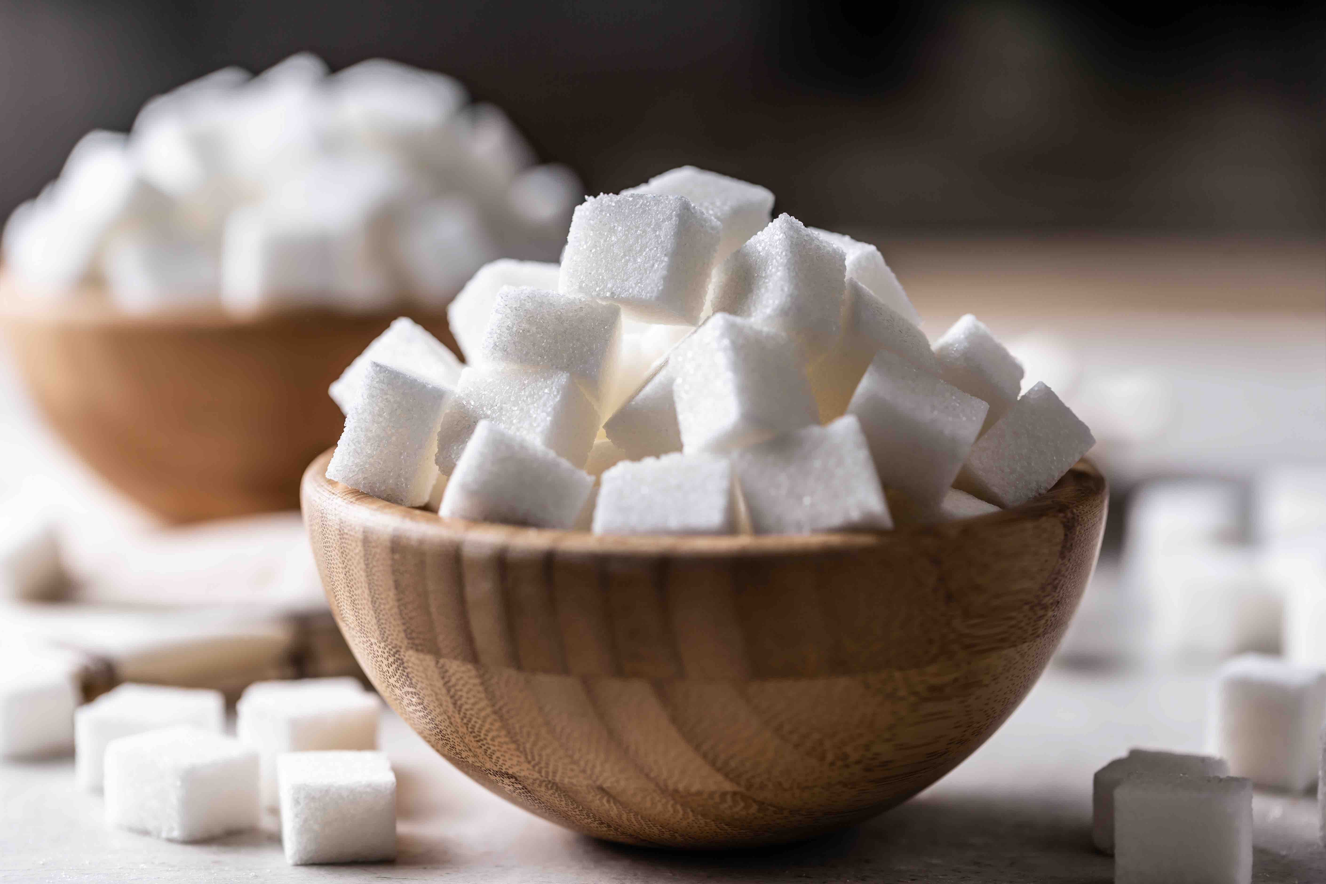 White sugar cubes in a wooden bowl on the table.