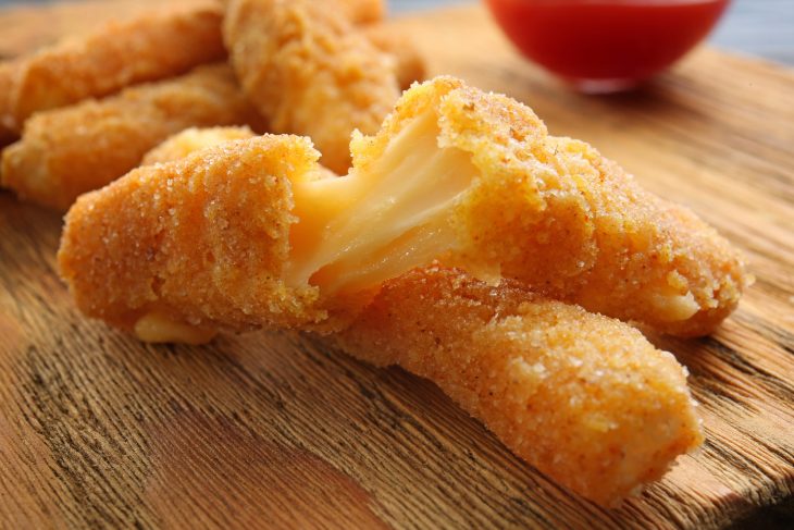 Fried cheese sticks on wooden cutting board
