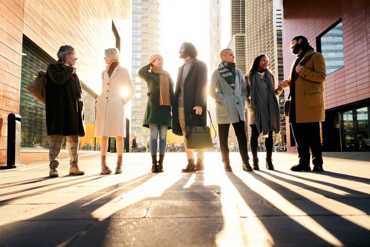 Silhouette of a group of business people full body talking outdoors in the city street. Man and woman corporate community.