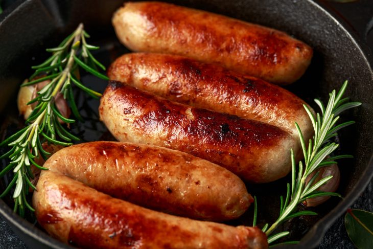 homemade sausages with rosemary in cast iron frying pan