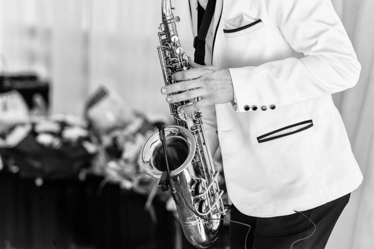 Saxophonist in white jacket plays the saxophone. Saxophonist jazz man with saxophone on wedding party