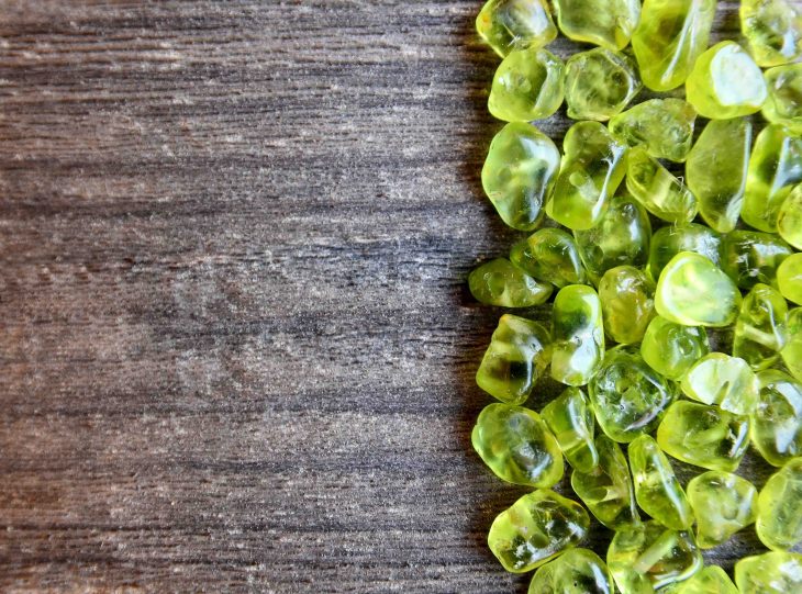 Olivine gemstone also called Peridot on old wooden background.Selective focus.